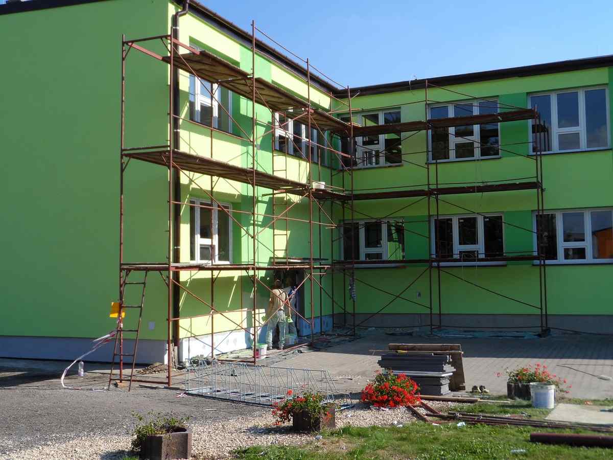 Bâtiment avec façade verte en rénovation, échafaudage métallique installé, matériel au sol