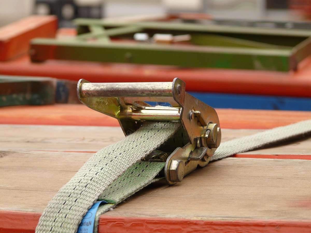 Sangle de fixation beige avec boucle métallique sur structure multicolore en bois et métal