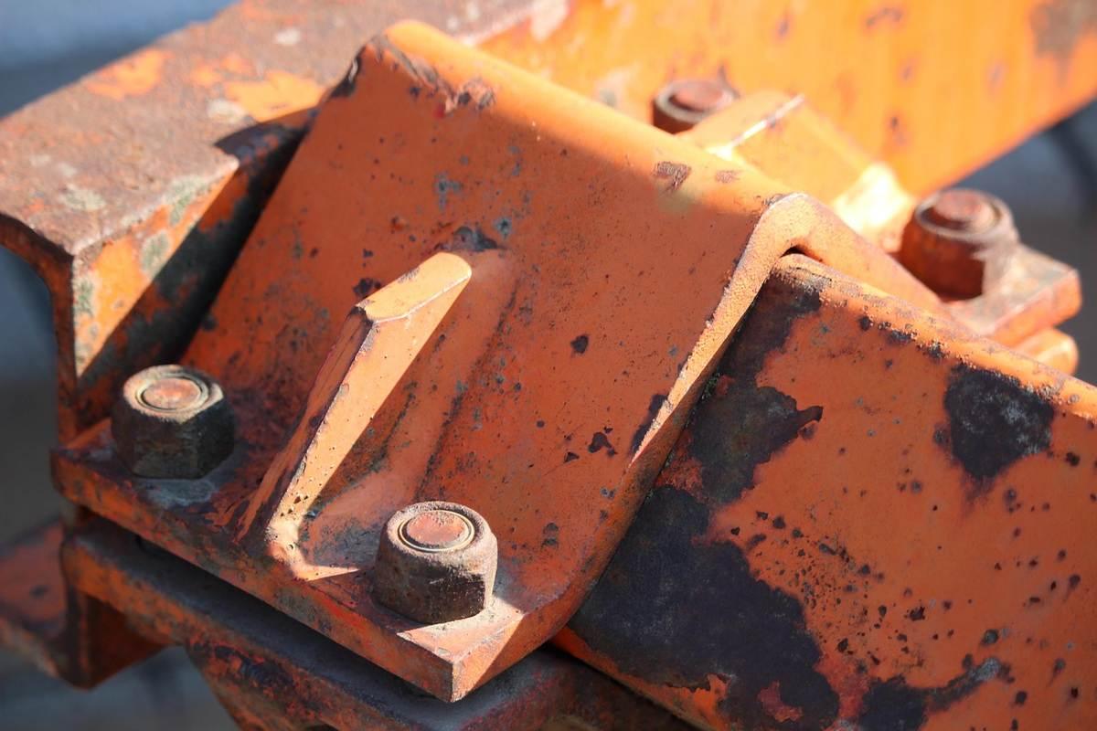 Pièces métalliques orange rouillées fixées par des boulons sur une structure extérieure