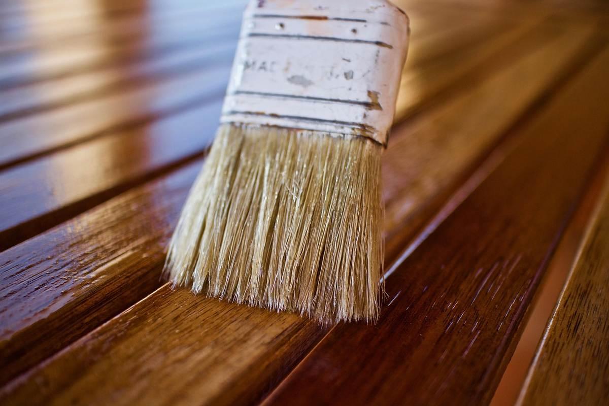 Pinceau appliquant une finition protectrice sur des lames de parquet en chêne verni