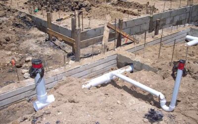 Fondations en béton avec tuyaux PVC et armatures métalliques sur un terrain en terre