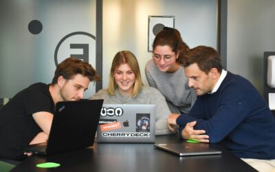 Four people collaborating around a laptop on a table in a modern office